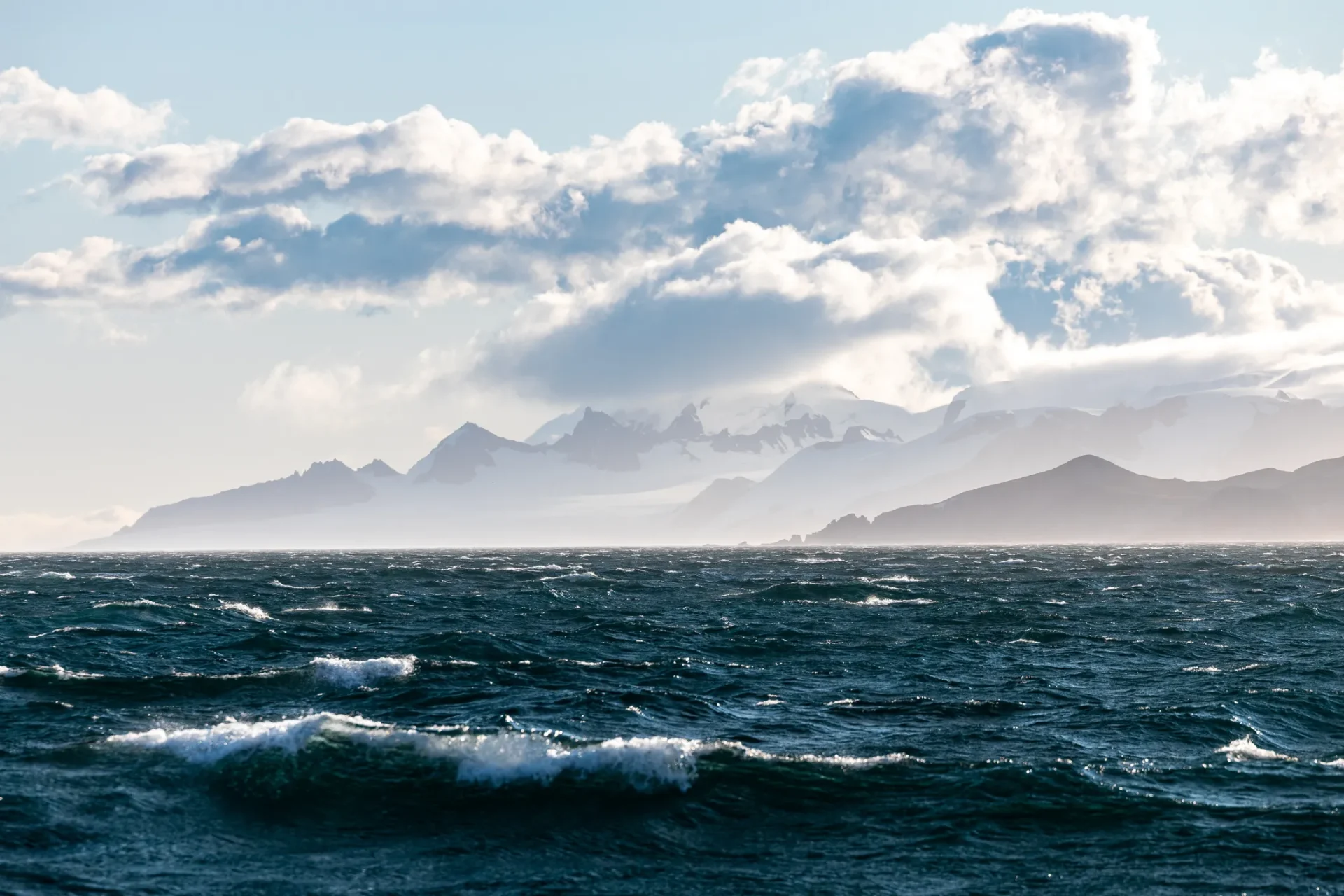 Misty mountains behind ocean waves
