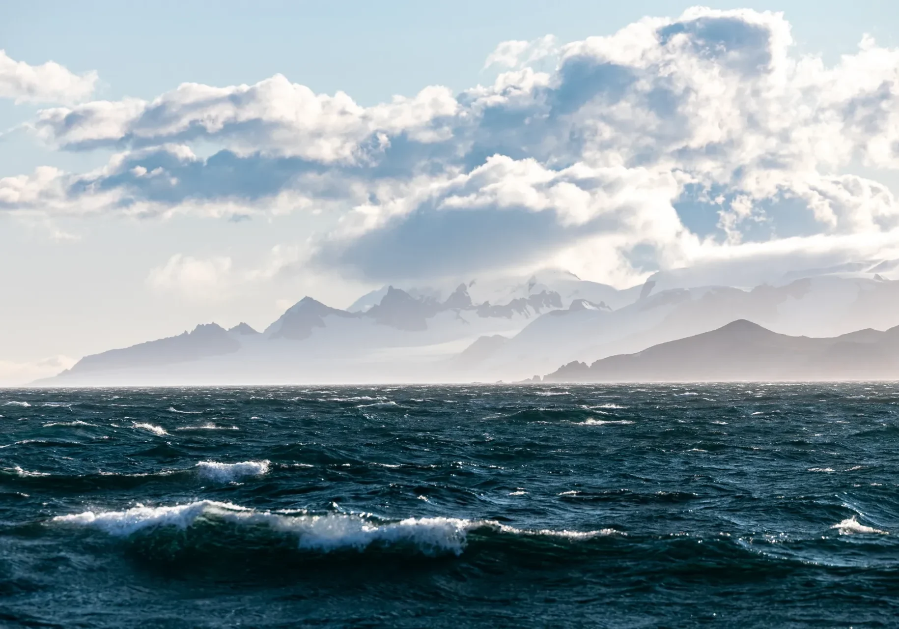 Misty mountains behind ocean waves